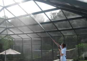 man spraying and cleaning screen pool enclosure lanai